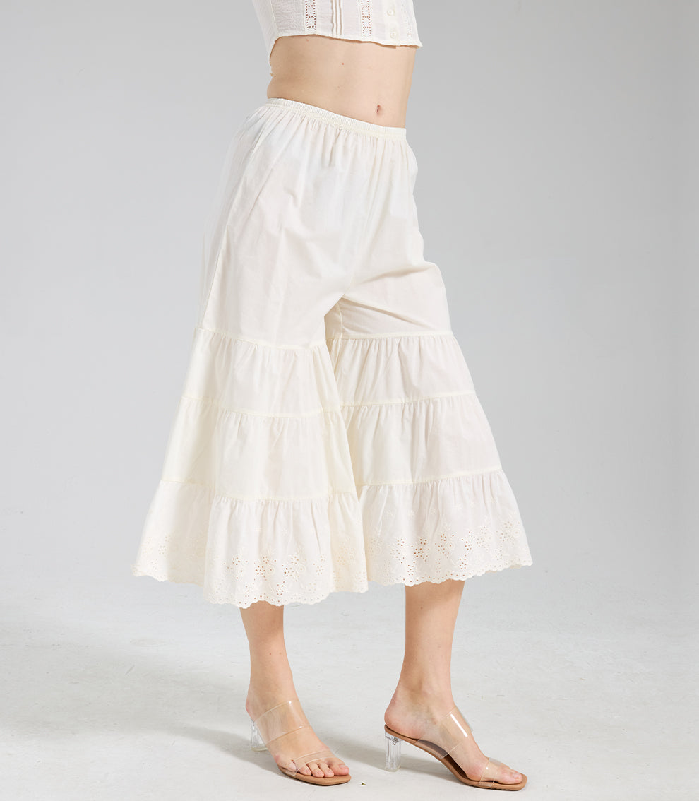 Side angle view of cream tiered pettipants showing the layered ruffle structure and wide-leg silhouette.
