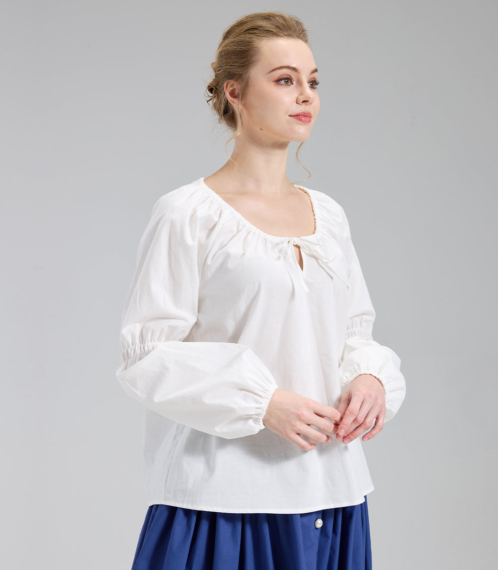 Three quarter angle of an ivory prairie blouse highlighting the long bishop sleeves, with the model's hands gently clasped.