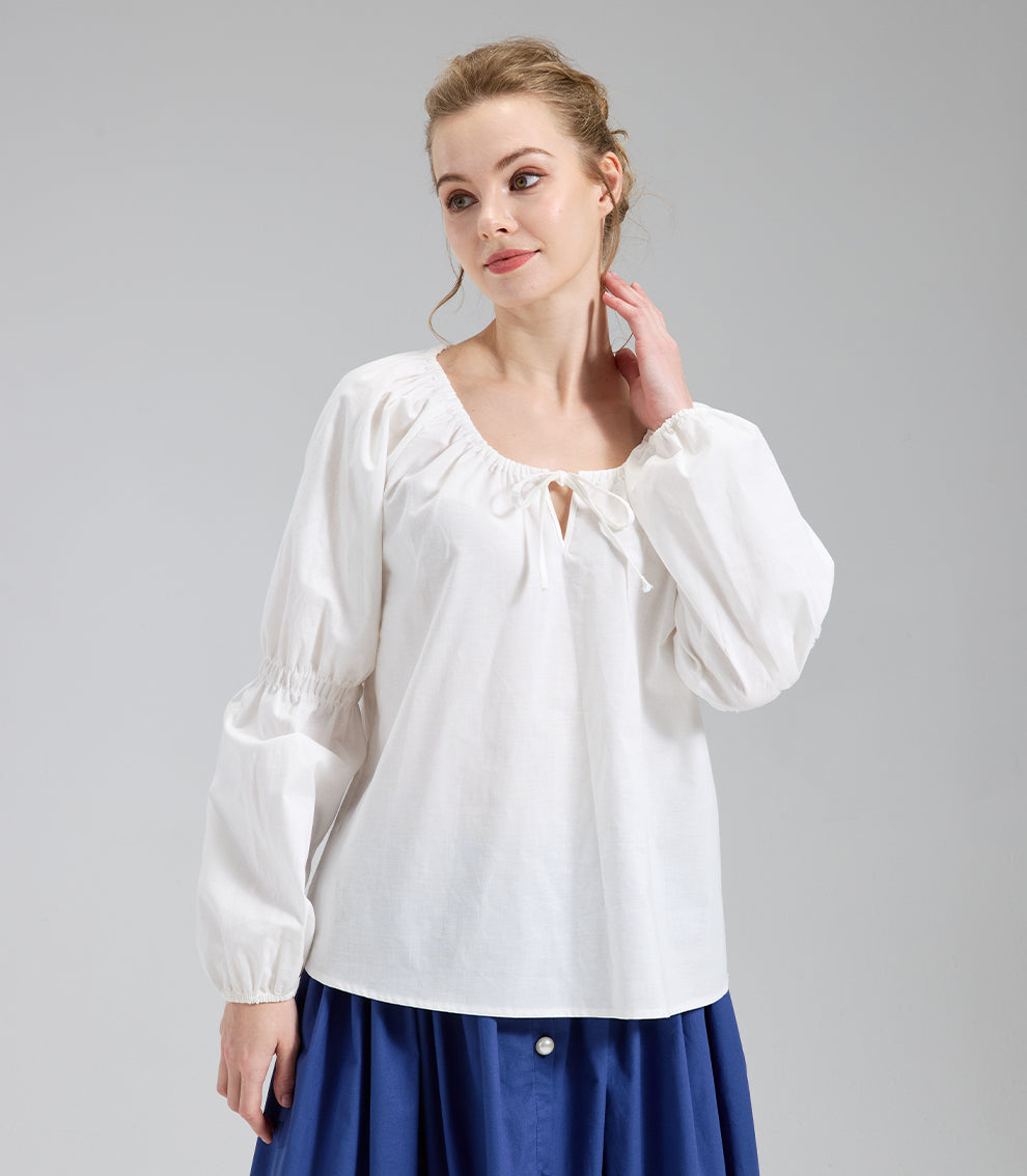 Close up of a medieval style ivory shirt for women, showing the draped neckline and relaxed fit on a grey background.