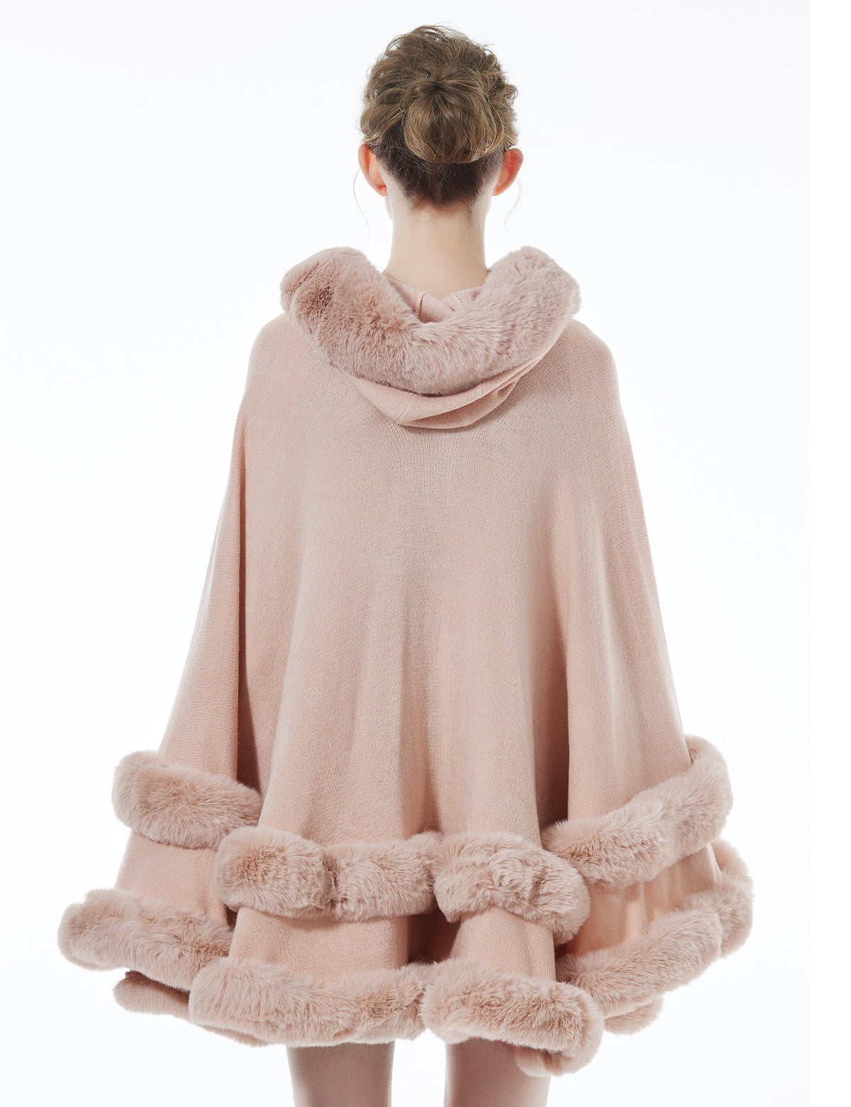 Back view of pink hooded knit cape displaying flowing silhouette and faux fur hood detail