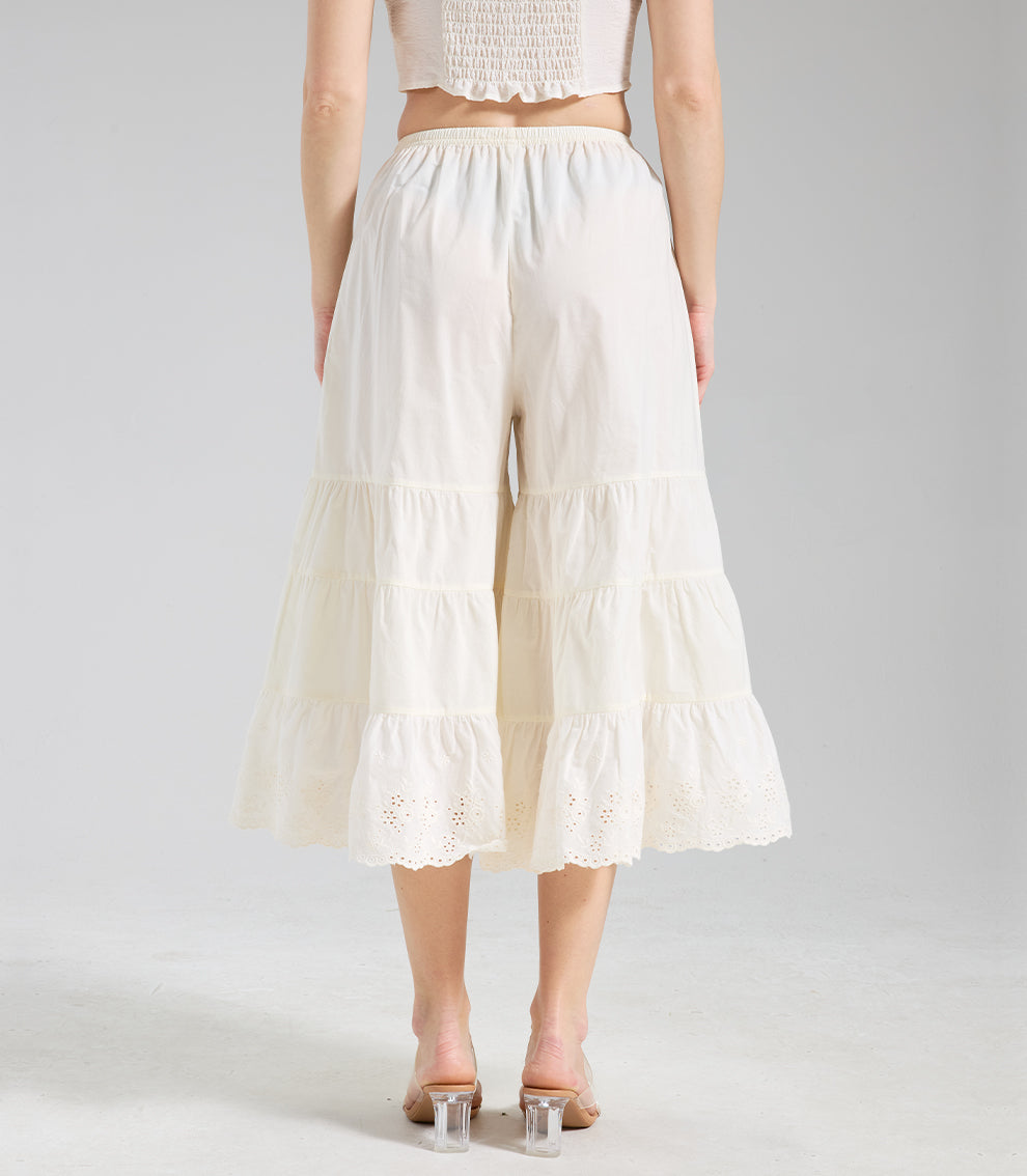 Straight back view of cream lace trim culottes emphasizing the symmetrical tiered structure and eyelet embroidery.