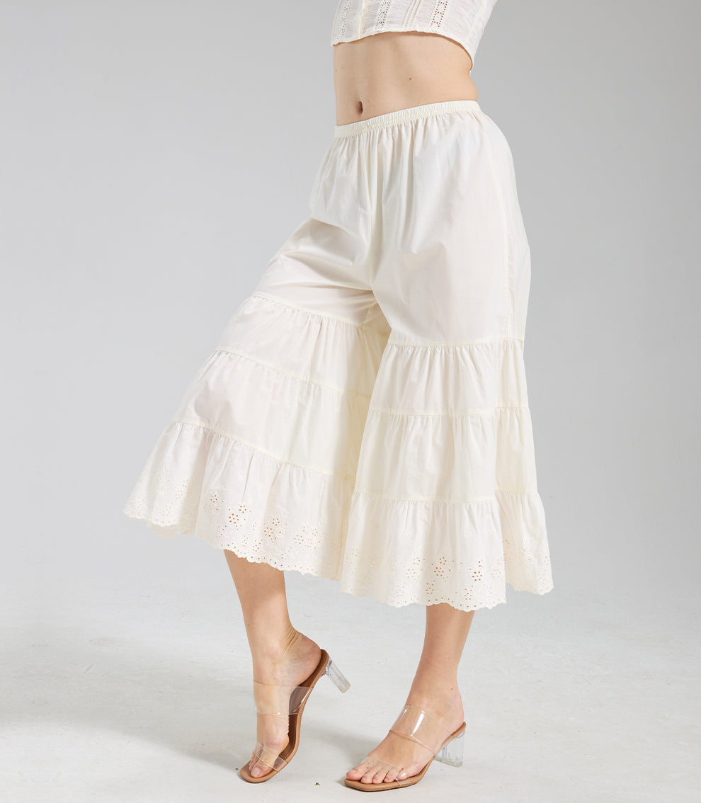 Side profile of cream vintage culottes highlighting the elegant drape of the tiered ruffles and lace trim.